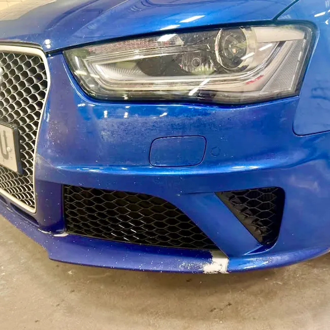 Close view of a blue Audi front bumper in the workshop