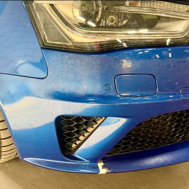 Blue Audi front bumper with visible bodywork damage