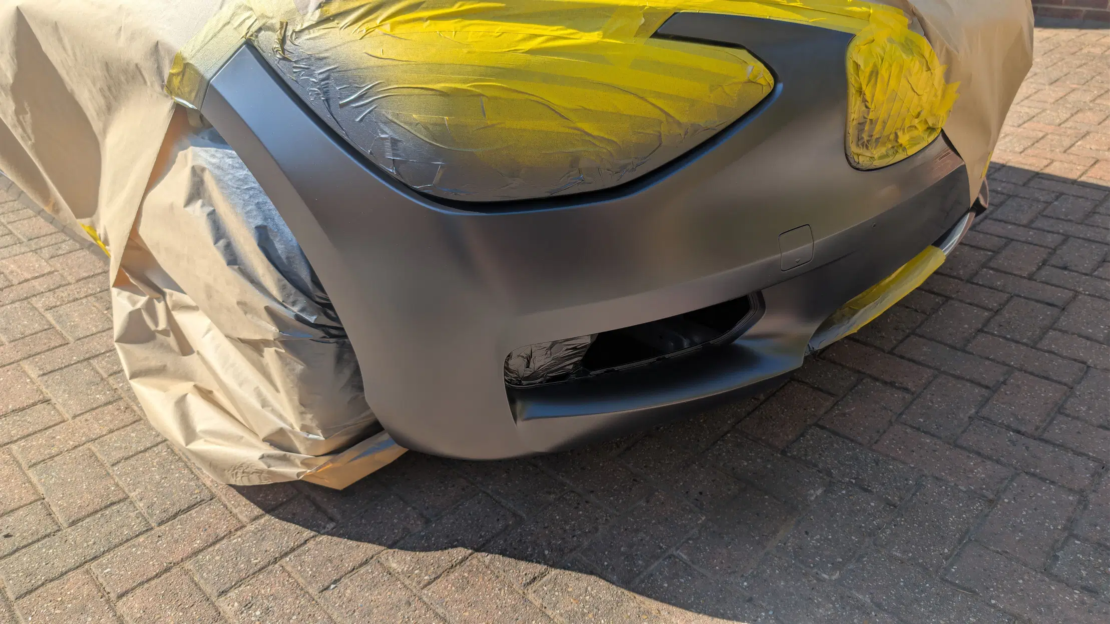 BMW bumper after paint repair, still masked for finishing