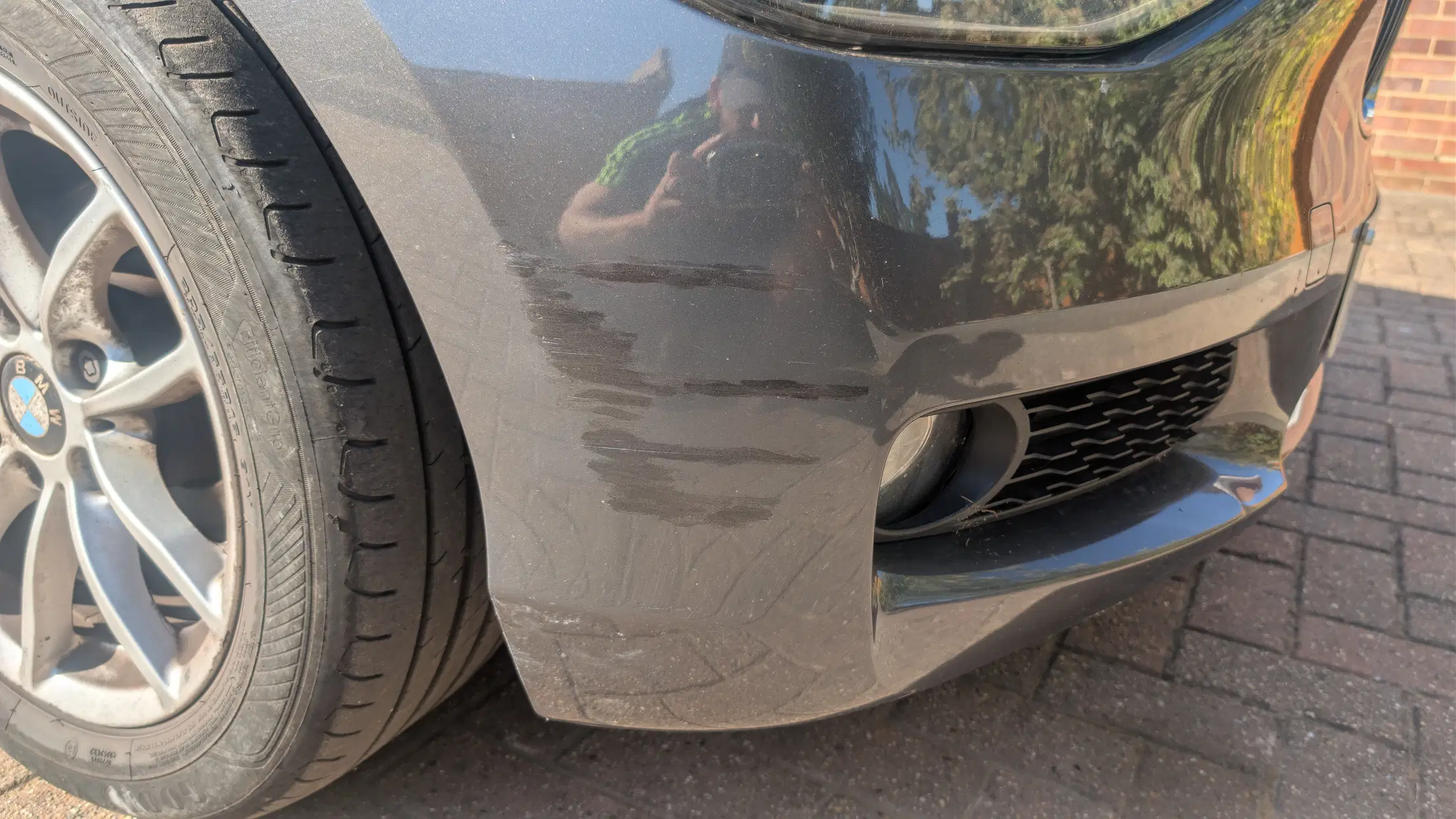 Scuff damage on the front bumper of a grey BMW