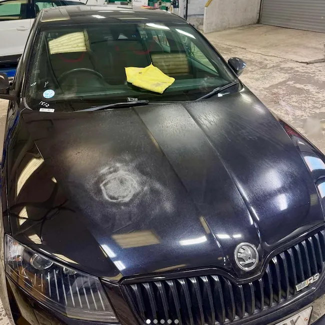 Dark Skoda with a marked bonnet awaiting repair
